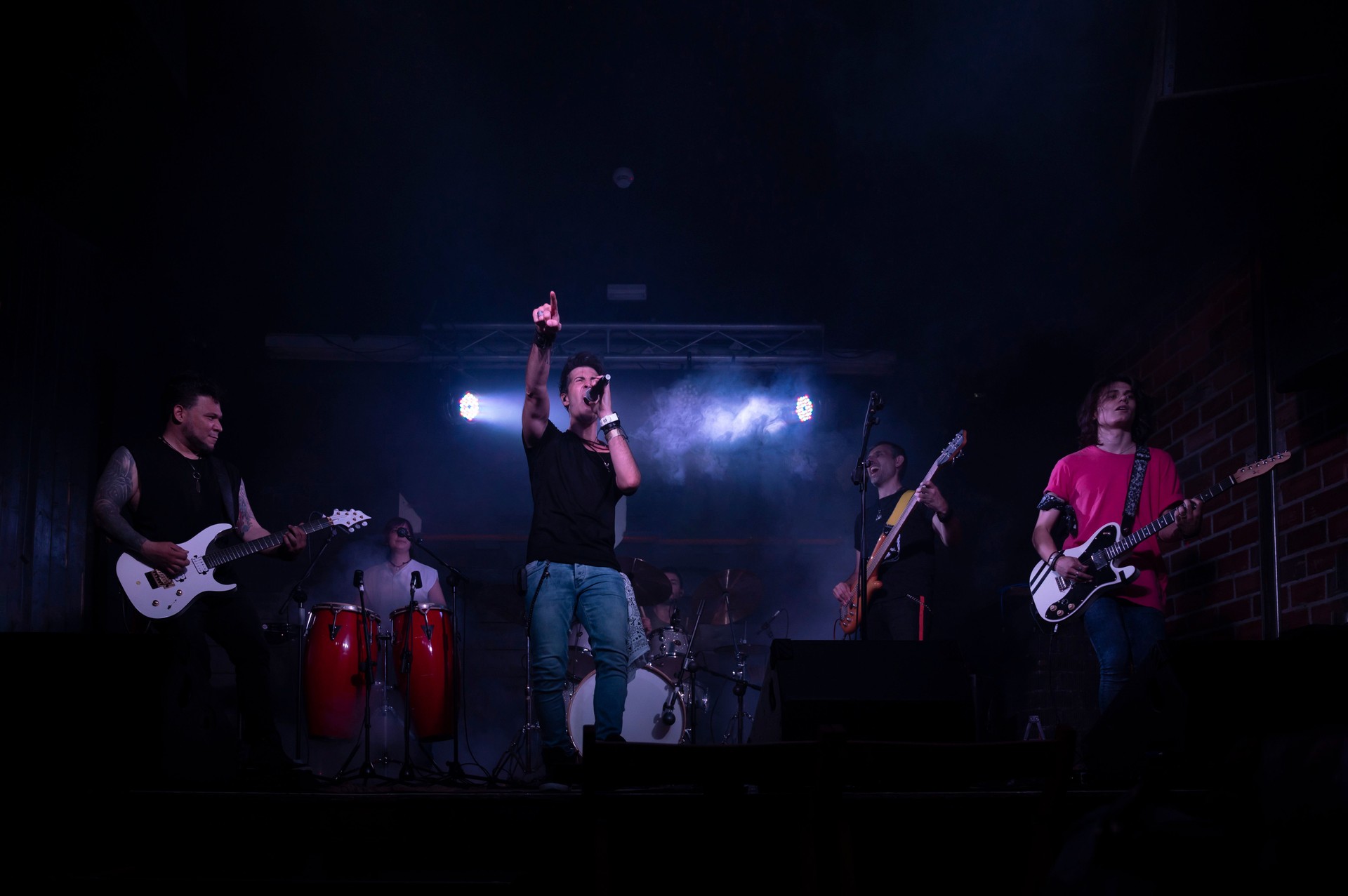 Young energetic rock band performing during a concert in a club